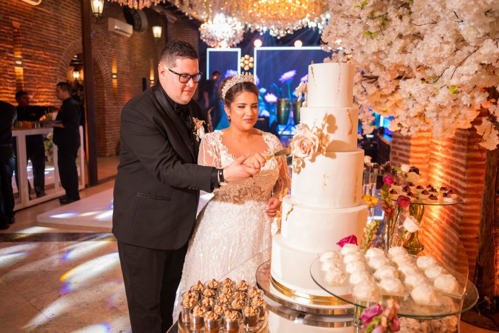 elegant-wedding-couple-cutting-cake-in-luxurious-setting-32142688