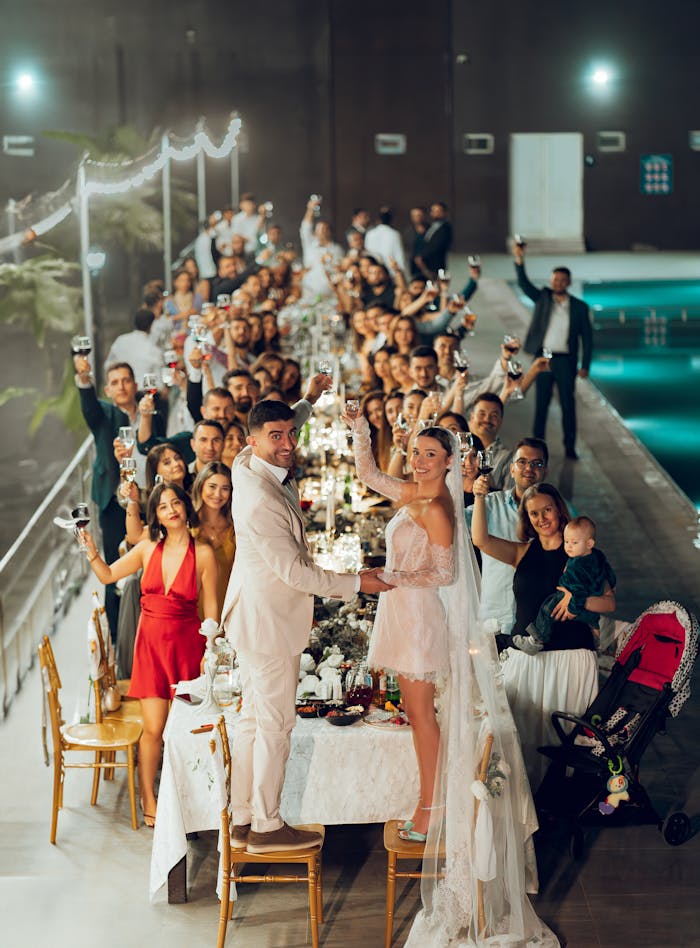 A lively wedding reception with guests toasting the newlyweds at night.