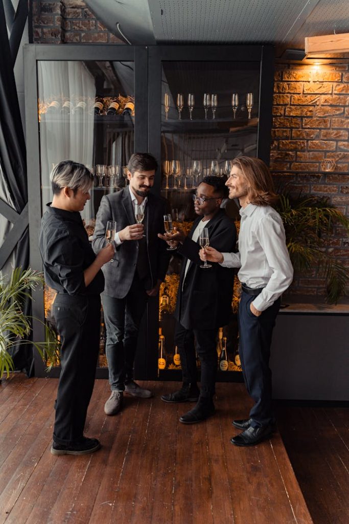 multiracial-group-of-men-holding-wine-glass-6759184 A diverse group of adults enjoying a toast in formal business attire, indoors.